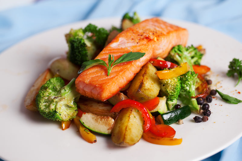 grilled salmon on top of a bed grilled vegetables