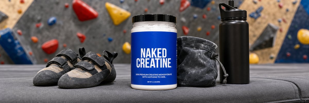 Naked Creatine tub on a crash pad at an indoor bouldering gym beside climbing shoes and chalk bag