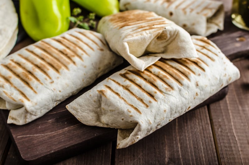 Wrapped black bean breakfast burritos on a wooden board