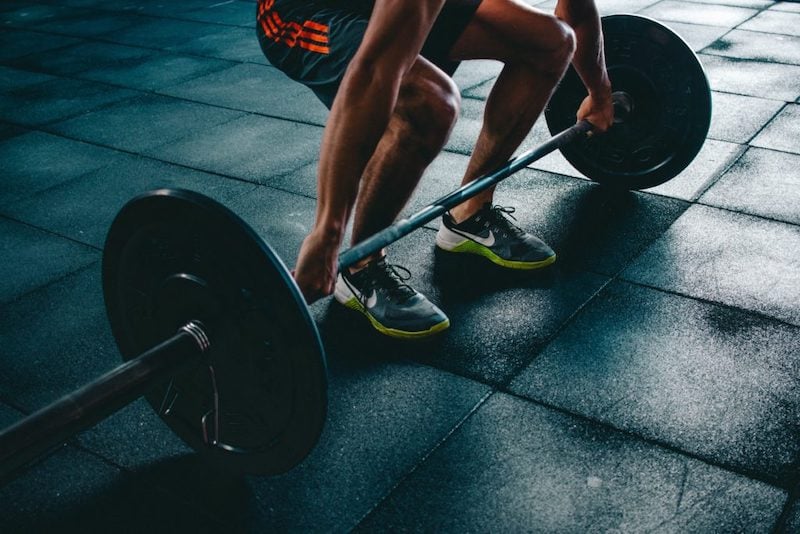 Hombre en el gimnasio preparándose para comenzar a levantar pesas