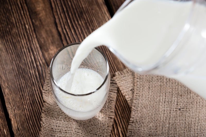 Full fat milk being poured into a glass from a jug