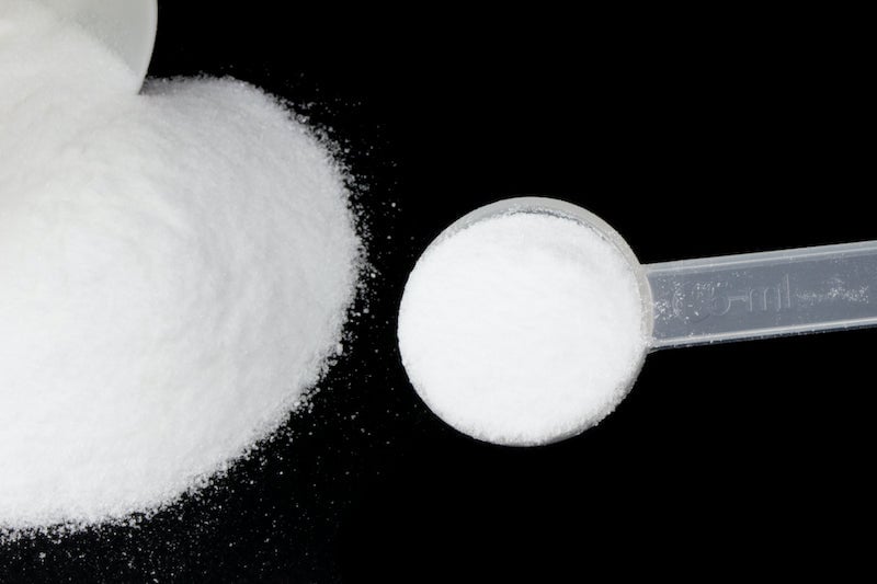 Pre-workout supplement powder in a small plastic scoop