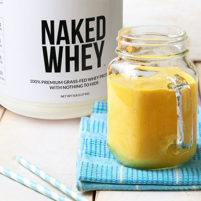 Batido de proteínas junto a un bote de Naked Whey sin sabor: un polvo de proteína de suero de leche alimentado con pasto